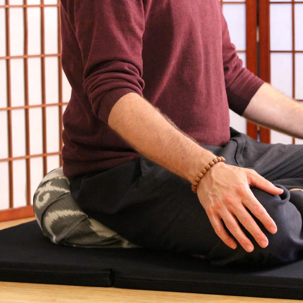 Person using travel zafu sitting on zabuton in lotus position