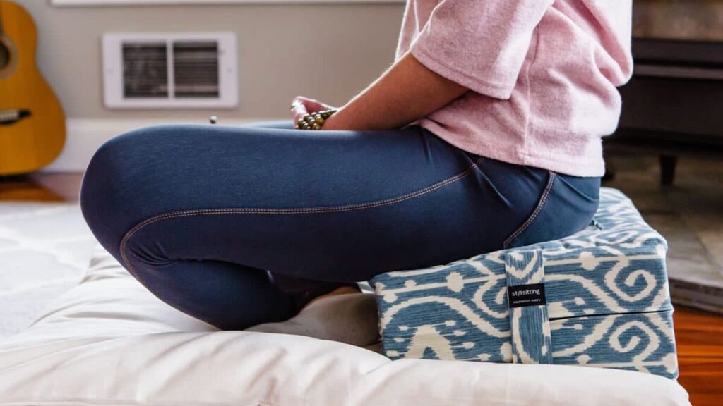 Woman sitting on Tibetan Seat and zabuton in nice meditation space, gomden style foam cushion on zabuton