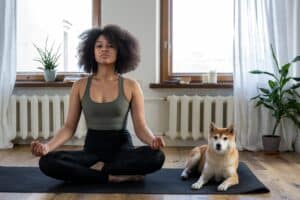 A woman doing meditation with her dog.